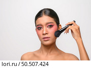 woman wearing pink makeup and holding a blush brush. Isolated on white background. Стоковое фото, агентство Ingram Publishing / Фотобанк Лори
