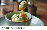 A close-up of a spoon swirling a fusion dessert miso caramel over matcha ice cream with a dusting of black sesame seeds, concept of unusual meal and food. Стоковое AI-видео, аниматор Sergey Grishin / Фотобанк Лори