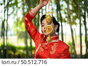 Portrait pretty Asian woman in a Chinese cheongsam smile and holding Golden amulet for Chinese New Year lucky symbol decorations, copy space. Стоковое фото, агентство Ingram Publishing / Фотобанк Лори
