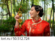 Portrait pretty Asian woman in a Chinese cheongsam smile and holding Golden amulet for Chinese New Year lucky symbol decorations, copy space. Стоковое фото, агентство Ingram Publishing / Фотобанк Лори