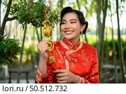 Portrait pretty Asian woman in a Chinese cheongsam smile and holding Golden amulet for Chinese New Year lucky symbol decorations, copy space. Стоковое фото, агентство Ingram Publishing / Фотобанк Лори