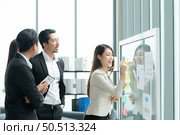 Young entrepreneurs in Asia Organize meetings to brainstorm and review information on glass board to get the best investment conclusion. Стоковое фото, агентство Ingram Publishing / Фотобанк Лори