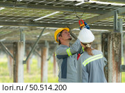 A team of electrical engineers is inspecting and maintaining solar panels at a solar panel site in the middle of a hundred acre field. Стоковое фото, агентство Ingram Publishing / Фотобанк Лори