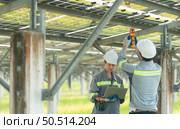 A team of electrical engineers is inspecting and maintaining solar panels at a solar panel site in the middle of a hundred acre field. Стоковое фото, агентство Ingram Publishing / Фотобанк Лори