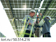 A team of electrical engineers is inspecting and maintaining solar panels at a solar panel site in the middle of a hundred acre field. Стоковое фото, агентство Ingram Publishing / Фотобанк Лори