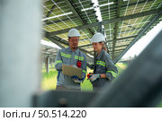 A team of electrical engineers is inspecting and maintaining solar panels at a solar panel site in the middle of a hundred acre field. Стоковое фото, агентство Ingram Publishing / Фотобанк Лори
