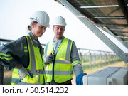 A team of electrical engineers is inspecting and maintaining solar panels at a solar panel site in the middle of a hundred acre field. Стоковое фото, агентство Ingram Publishing / Фотобанк Лори