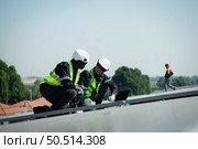 Both of Engineer in charge of solar panel installation The installation of solar energy conversion into electricity for a warehouse is currently being investigated. Стоковое фото, агентство Ingram Publishing / Фотобанк Лори