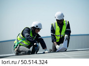 Both of Engineer in charge of solar panel installation The installation of solar energy conversion into electricity for a warehouse is currently being investigated. Стоковое фото, агентство Ingram Publishing / Фотобанк Лори
