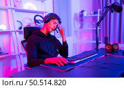 Gamer holding his head with both hands and having a frustrated mood unpleasant when playing a game losing to an opponent. Стоковое фото, агентство Ingram Publishing / Фотобанк Лори