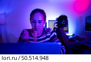 Asian women who rely heavily on computers to watch drama series until having to eat instant noodles in front of it, The game room has computers and LED neon lights that are spectacular. Стоковое фото, агентство Ingram Publishing / Фотобанк Лори