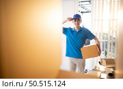 The delivery man brings the goods that the customer purchased and delivers them to the customer’s home. Стоковое фото, агентство Ingram Publishing / Фотобанк Лори