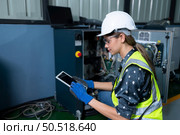 Female Technician Inspecting and repairing robotics arm in robots hangar and test the operation of the machine after being used for a while, as well as updating the software and calibration. Стоковое фото, агентство Ingram Publishing / Фотобанк Лори