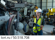 A female engineer installs a program on a robotics arm in a robot warehouse. And test the operation before sending the machine to the customer. Стоковое фото, агентство Ingram Publishing / Фотобанк Лори