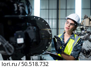 A female engineer installs a program on a robotics arm in a robot warehouse. And test the operation before sending the machine to the customer. Стоковое фото, агентство Ingram Publishing / Фотобанк Лори