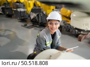A female engineer installs a program on a robotics arm in a robot warehouse. And test the operation before sending the machine to the customer. Стоковое фото, агентство Ingram Publishing / Фотобанк Лори