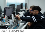 The robotic hand technology teacher is instructing new students on how to use electronic circuit boards and robotic hand commands for a variety of industrial applications. Стоковое фото, агентство Ingram Publishing / Фотобанк Лори