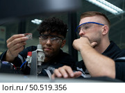 The robotic hand technology teacher is instructing new students on how to use electronic circuit boards and robotic hand commands for a variety of industrial applications. Стоковое фото, агентство Ingram Publishing / Фотобанк Лори