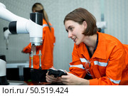In an electronic parts facility, two female engineers In the plant, inspecting and testing robotic hands used in the production of electronic components. Стоковое фото, агентство Ingram Publishing / Фотобанк Лори