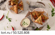 Indian samosas  - fried or baked pastry with savoury filling, popular Indian snacks, served in areca leaf dishes with spices on kitchen countertop. Стоковое фото, агентство Ingram Publishing / Фотобанк Лори