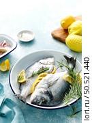 Fresh raw dorado fish cooking with lemon and rosemary. Sea bream, dorado. Seafood, healthy food. Стоковое фото, агентство Ingram Publishing / Фотобанк Лори