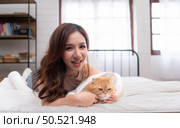 An intelligent Persian cat and owner playing together in bed. Стоковое фото, агентство Ingram Publishing / Фотобанк Лори