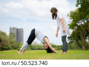 Young female and little girl with outdoor activities in the city park, Yoga is her chosen activity. Стоковое фото, агентство Ingram Publishing / Фотобанк Лори