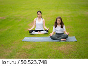 Young female and little girl with outdoor activities in the city park, Yoga is her chosen activity. Стоковое фото, агентство Ingram Publishing / Фотобанк Лори