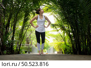 Young female in the garden there are wooden walkways and a tunnel of fresh green trees, with yoga activities for health. Стоковое фото, агентство Ingram Publishing / Фотобанк Лори