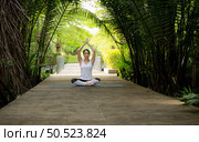 Young female in the garden there are wooden walkways and a tunnel of fresh green trees, with yoga activities for health. Стоковое фото, агентство Ingram Publishing / Фотобанк Лори