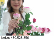 ?Young woman florist smelling a red rose in the flower shop. Стоковое фото, агентство Ingram Publishing / Фотобанк Лори