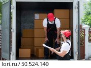 Delivery man in red cap and uniform delivering parcel to recipient - courier service concept. Стоковое фото, агентство Ingram Publishing / Фотобанк Лори