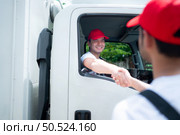 Delivery man in red cap and uniform handshaking each other after finishing deliveries. Стоковое фото, агентство Ingram Publishing / Фотобанк Лори