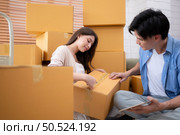 Young asian couple checking boxes being transported into new home with tablet. Стоковое фото, агентство Ingram Publishing / Фотобанк Лори