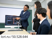 Diverse team of businessmen and engineers consultation on the engineering of a wind turbine that converts wind energy to electricity in the office. Стоковое фото, агентство Ingram Publishing / Фотобанк Лори