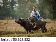 woman sitting on the back of a buffalo in the meadow. Стоковое фото, агентство Ingram Publishing / Фотобанк Лори