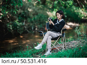 Young pretty woman use digital camera taking a photo beautiful nature while camping in forest with happiness, copy space. Стоковое фото, агентство Ingram Publishing / Фотобанк Лори