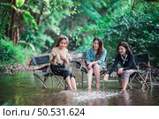 Group of young asian women sitting in their chairs with beer and enjoy to splashing water in the stream while camping in the nature park, They are talking and laugh fun together. Стоковое фото, агентство Ingram Publishing / Фотобанк Лори