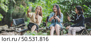 Group of young asian women drink beer in their chairs and soaked their feet in the stream while camping in the nature park, They are enjoy to talking and laugh fun together. Стоковое фото, агентство Ingram Publishing / Фотобанк Лори