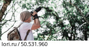 Asian traveler man with backpack taking a photo in the park with copy space. Travel photographer. Vocation and holiday concept. Стоковое фото, агентство Ingram Publishing / Фотобанк Лори