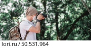 Asian traveler man with backpack taking a photo in the park with copy space. Travel photographer. Vocation and holiday concept. Стоковое фото, агентство Ingram Publishing / Фотобанк Лори