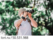 Asian traveler man with backpack taking a photo in the park. Travel photographer. Vocation and holiday concept. Стоковое фото, агентство Ingram Publishing / Фотобанк Лори