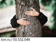 Contented young woman hugging a large tree with a blissful expression. Concept of care for environment. Стоковое фото, агентство Ingram Publishing / Фотобанк Лори