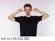 Portrait of attractive man close ears from noisy neighbours, looking up and shouting annoyed, hearing loud music on isolated background. . Стоковое фото, агентство Ingram Publishing / Фотобанк Лори