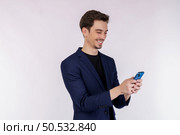 Portrait of a happy businessman using smartphone over white background. Using mobile phone, typing sms message. Стоковое фото, агентство Ingram Publishing / Фотобанк Лори