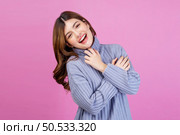 Portrait of Smiling young woman sweet winsome lovely attractive charming cheerful cheery lady hugging herself isolated over pink background. People lifestyle and expression concept. Стоковое фото, агентство Ingram Publishing / Фотобанк Лори