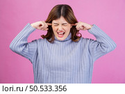 Portrait of Annoyed woman sticking plug fingers in ears not listening to loud noise sound isolated over pink background. Refuse hear avoid stress feel ear pain ache concept. Стоковое фото, агентство Ingram Publishing / Фотобанк Лори