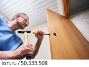 Chiseling groove in door frame to fit metal latch plate allowing flush mounting and smooth operation of lock performed by experienced craftsman. Стоковое фото, фотограф Владимир Григорьев / Фотобанк Лори