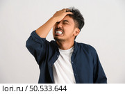 Portrait of Disappointed young asian man in blue shirt annoyed angry in furious gesture isolated on white background. Expression and lifestyle concept. Стоковое фото, агентство Ingram Publishing / Фотобанк Лори