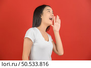 Portrait of Excited young asian woman in white t-shirt shout story or making announcement over isolated white background. Advertising and lifestyle concept. Стоковое фото, агентство Ingram Publishing / Фотобанк Лори